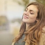Portrait of a woman with closed eyes, enjoying the outdoors in autumn. Bright and serene.